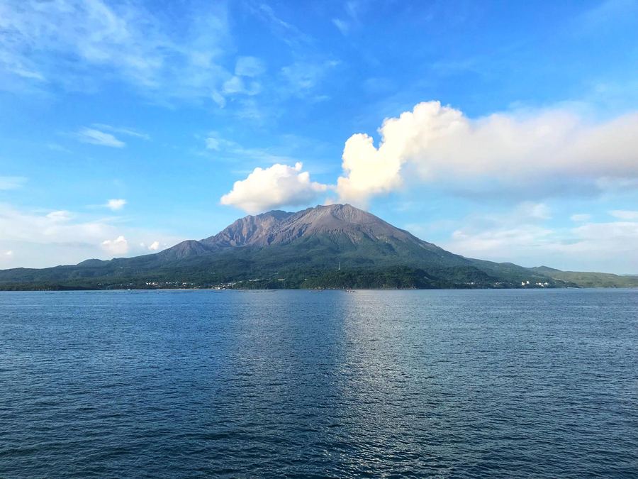 錦江湾越しに望む桜島。山頂から噴煙がたなびいている